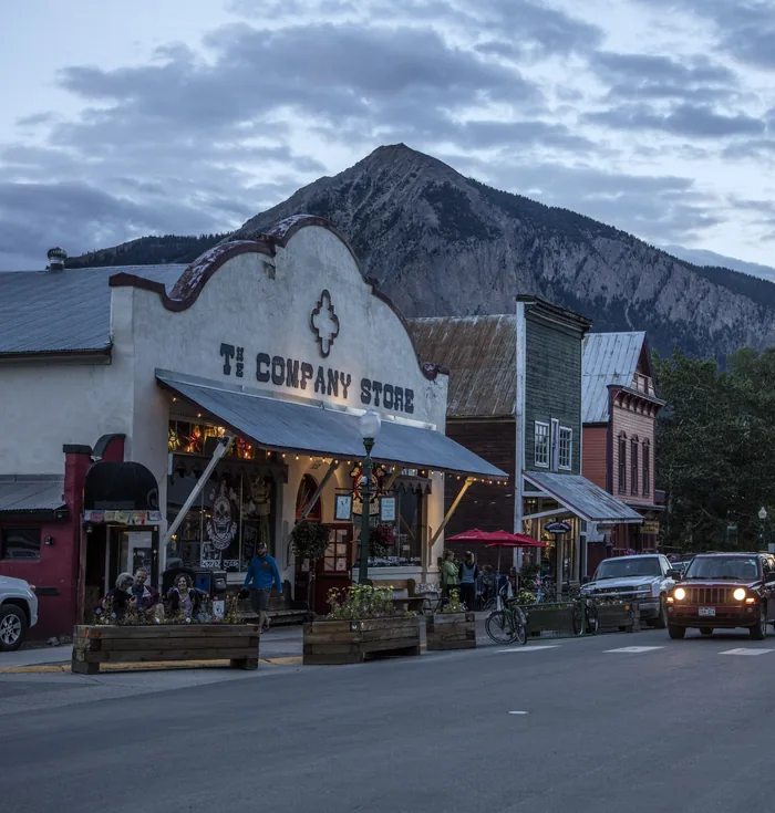Elk Avenue in Crested Butte at dusk, with the old company store lit up and Mount Crested Butte behind
